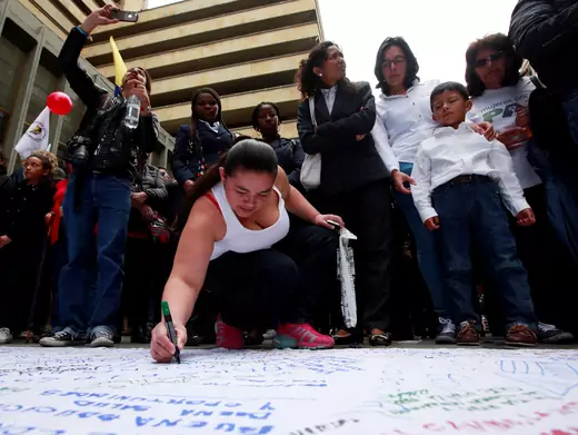 A woman writes a message about peace on a banner as people celebrate the signing of a historic ceasefire deal between the Colombian government and FARC rebels in Bogota, Colombia, June 23, 2016. 