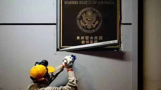 A worker removes a plaque from the U.S. consulate in Chengdu.