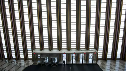 From a zoomed-out, interior perspective, a man walks out of the UN headquarters.