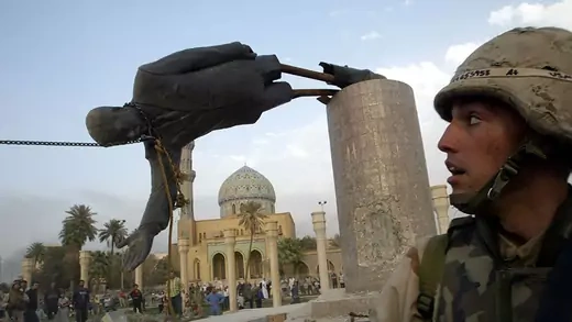 An American soldier looks on as a statue of Saddam Hussein is toppled