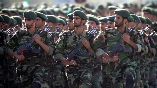 Members of the Iranian Revolutionary Guard Corps hold guns while marching in a parade