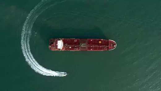 Aerial shot of a small boat circling a red tanker