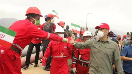 Venezuela oil company employees wearing masks wave Iranian flags. One fist-bumps Venezuelan Oil Minister Tareck El Aissami.