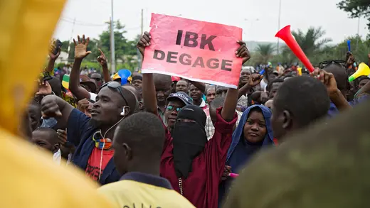 A woman holds up a sign that reads "IBK, clear out" during a protest calling for President Ibrahim Boubacar Keita to resign, in Bamako on August 11, 2020.
