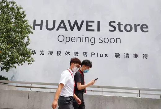 People walk past an advertisement announcing the opening of a Huawei store.