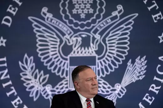 Secretary of State Mike Pompeo sits on stage in front of a large State Department logo before giving remarks on the draft report of the U.S. Commission on Unalienable Rights.