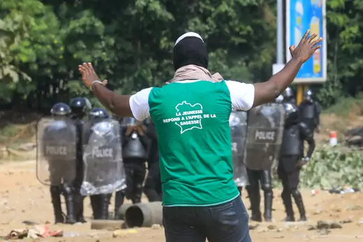A demonstrator gestures in front of policemen during a protest against President Alassane Ouattara's decision to stand for a third term, in Abidjan, Ivory Coast, August 13, 2020.