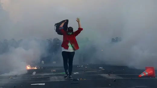 A protester walks against a backdrop of police-fired tear gas in Minneapolis, Minnesota. Protests were incited across the United States after the police killing of George Floyd, a Black man held in Minneapolis police custody, in May 2020.