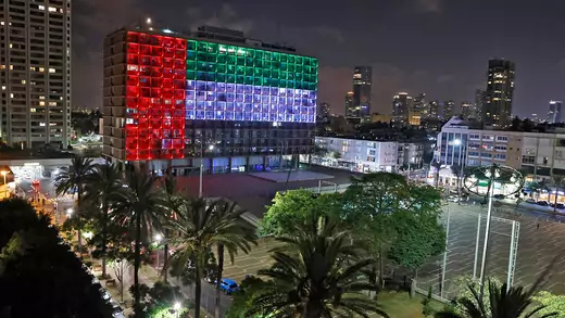 Nachts ist das mehrstöckige Rathausgebäude in Tel Aviv so beleuchtet, dass es der Flagge der Vereinigten Arabischen Emirate ähnelt