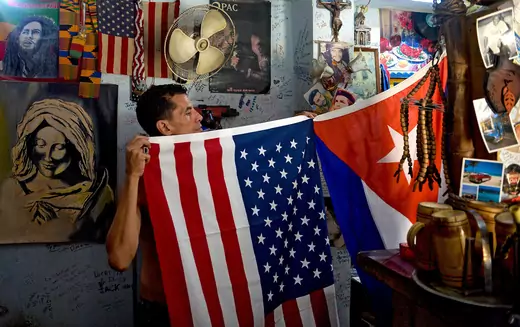 A man shows U.S. and Cuban flags at his house in Havana.
