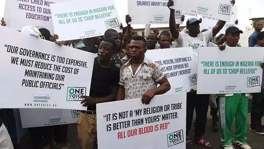 Male protestors in Lagos protest against the government. The front sign reads "It is not a 'my religion or tribe is better than yours' matter. All our blood is red."