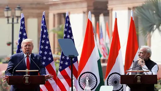 U.S. President Donald Trump and India's Prime Minister Narendra Modi stand next to each other in front of a row of U.S. and India flags.