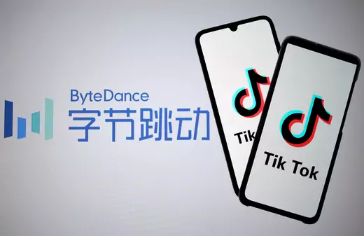 TikTok logos are seen on smartphones in front of a displayed ByteDance logo.