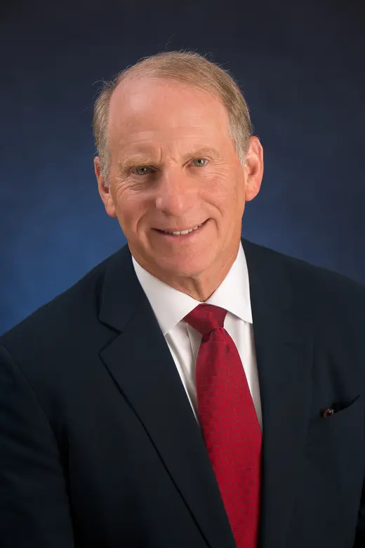 Headshot of CFR President Richard N. Haass wearing a black jacket, white shirt, and red tie, against dark blue background
