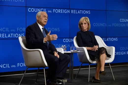 Colin Powell and Andrea Mitchell, both in black, sit on white chairs in front of a blue Council on Foreign Relations background