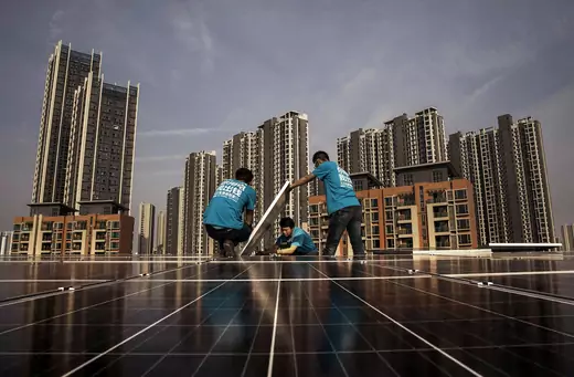 Three workers install a solar panel on the roof of a building in Wuhan, China.