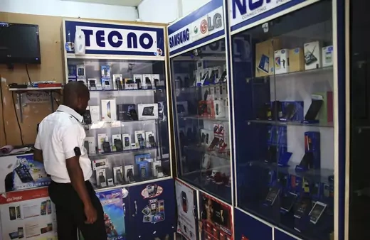 A man looks at smartphones on display at a shop.