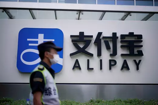 A security guard walks past an Alipay logo at the office of Alipay.