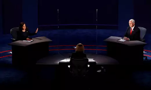 Senator Kamala Harris and Vice President Mike Pence sit across from each other separated by plexiglass on the stage of the vice-presidential debate.