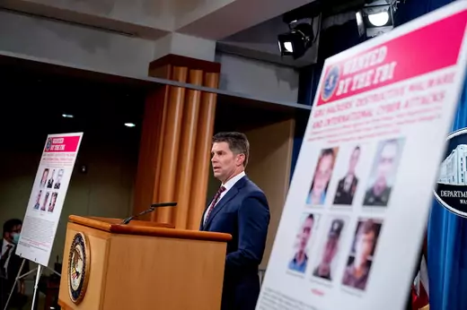 Posters showing six wanted Russian military intelligence officers are displayed as FBI Deputy Director David Bowdich speaks at a news conference at the Department of Justice, in Washington, U.S., October 19, 2020.