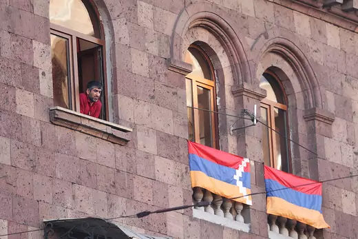 A man looks out of his window as a rally against the Nagorno-Karabakh peace deal takes place outside the Armenian National Assembly building.