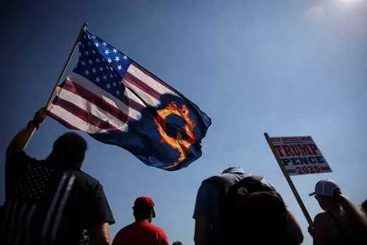 A supporter of President Donald Trump holds an U.S. flag with a reference to QAnon during a Trump 2020 Labor Day cruise rally.