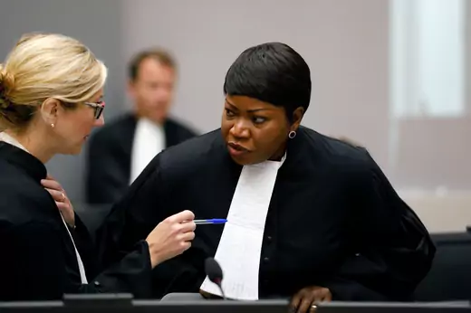 International Criminal Court (ICC) Prosecutor Fatou Bensouda is seen consulting with another ICC employee. Ms. Bensouda is wearing judicial garb.