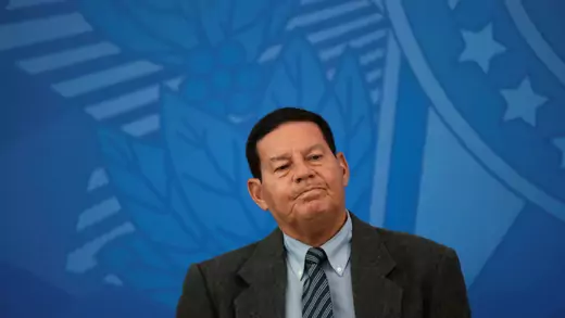 Vice President Hamilton Mourão of Brazil stands in front of a blue backdrop