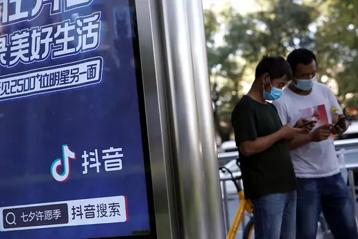 People wearing face masks following the coronavirus disease (COVID-19) outbreak use smartphones next to an advertisement of TikTok.