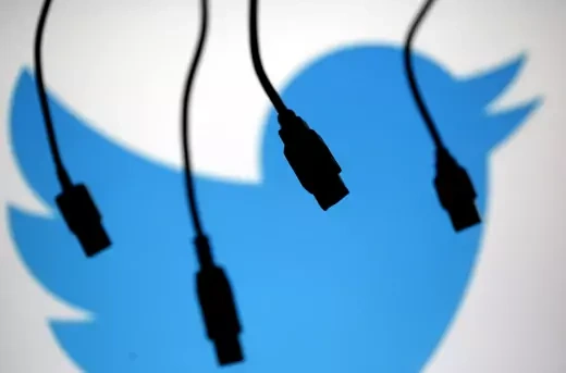 Electronic cables are silhouetted next to the logo of Twitter.