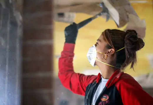 An Americorps volunteer uses a hammer while renovating a house 