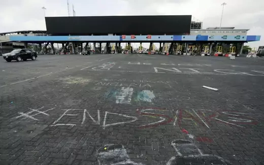 A picture of the Lekki Toll Gate in Lagos, Nigeria, the site of a killing of peaceful protesters by the Nigerian military. The #EndsSARS hashtag is seen written in chalk on the ground in the foreground of the picture.