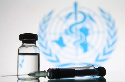 A medical syringe and a vial in front of the World Health Organization (WHO) logo are seen in this creative photo taken on 18 November 2020. Pfizer and Biontech announced its conclude phase 3 study of COVID-19 vaccine candidate with 95% primary efficacy analysis, as media reported on 18 November 2020.