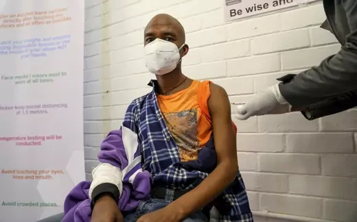 A South African man wearing a mask receiving an experimental COVID-19 vaccine.