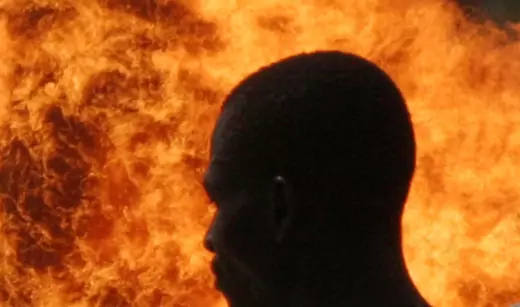 A man is seen walking by a massive flame, the result of gas flaring in the Niger Delta.