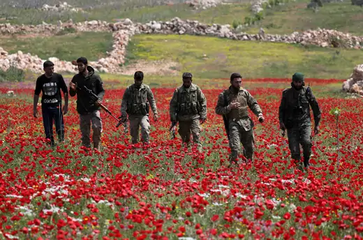 Turkey-backed Syrian rebel fighters walk in a field of flowers in Idlib, Syria, on April 15, 2020.