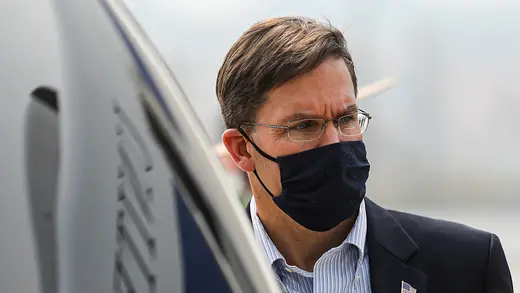 A close-up shot of Defense Secretary Mark T. Esper wearing a black face mask, glasses, and a suit.