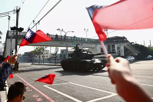 People wave flags while soldiers driving tanks pass on a street as part of a military drill in Taichung, Taiwan, on November 3, 2020.
