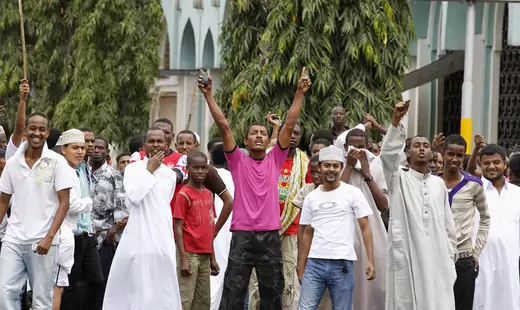 A group of Muslim youth are seen protesting the killing of a radical Kenyan imam, Aboud Rogo Mohammed. Several are wearing Islamic dress while others are wearing everyday clothing.