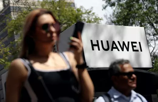 People walk past a Huawei company logo at a bus stop in Mexico City on February 22, 2019.
