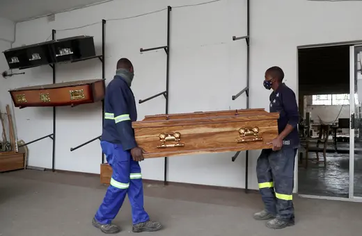 Two workers are seen carrying a casket in South Africa amid a nationwide lockdown in response to the rapid spread of a new COVID-19 variant. 