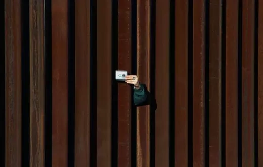 A woman in the United States takes a picture to Mexico through the border fence as residents of Anapra, a neighbourhood on the outskirts of Ciudad Juarez in Mexico, and other people attend a prayer with priests and bishops from both countries to ask for the migrants and people of the area, on February 26, 2019. - Built two years ago, the Anapra fence is one of several reinforced border barriers that the administration of US President Donald Trump calls the first sections of the wall.