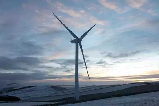 Wind turbines harnessing the natural green energy in the Scottish Borders on 28th December 2020 in Galashiels, Scotland, United Kingdom. The wind farm, Longpark Wind Farm, is long established and part of the renewable energy production in Scotland. The farm sits in the hills above the village Stow, near Galashields in the Scottish Borders. In between the wind turbines sheep grass in the fields lightly covered by snow.