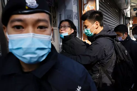 Hong Kong police force a man's arms behind his back, as an officer stands close to the camera, in Hong Kong.
