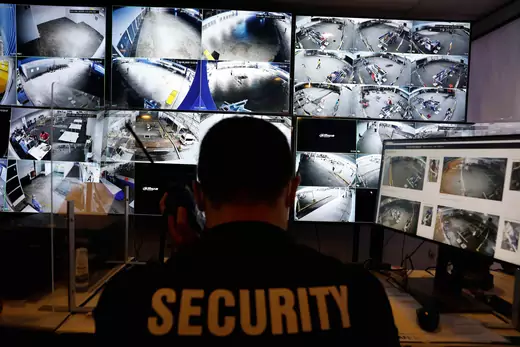 A security officer monitors surveillance cameras with geo-fencing and crowd monitoring capabilities.