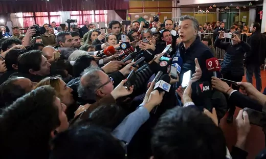 Mauricio Macri gives comment to dozens of reports surrounding him in a semicircle. 