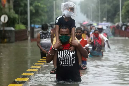 A man carries a child through a waterlogged road after heavy rainfall in Mumbai, India on September 23, 2020.