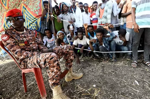 A Sudanese military officer keeps guard as Ethiopians who fled war in Tigray region, gather to receive relief supplies from the World Food Programme at the Fashaga camp on the Sudan-Ethiopia border in Al-Qadarif state, Sudan November 20, 2020.