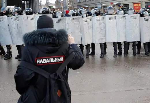 A demonstrator stands in front of law enforcement officers during a rally in support of jailed Russian opposition leader Alexei Navalny in Saint Petersburg, Russia on January 31, 2021. The writing on the jacket reads: 'Navalny'.
