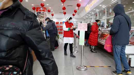 Customers wearing face masks at a food store decorated with red lanterns in China.
